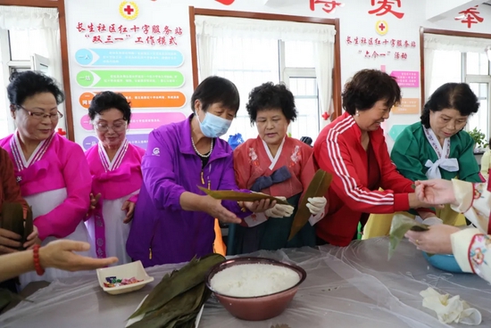 ▲延吉市建工街道长生社区汉族老人向朝鲜族老人传授包粽子技艺。
