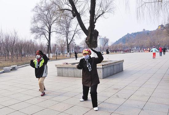 市民们在人民广场打太极拳、跳广场舞。