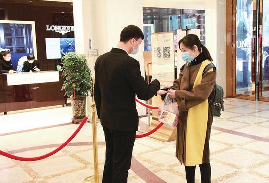 吉林国贸购物中心工作人员正在为前来购物的顾客测量体温。