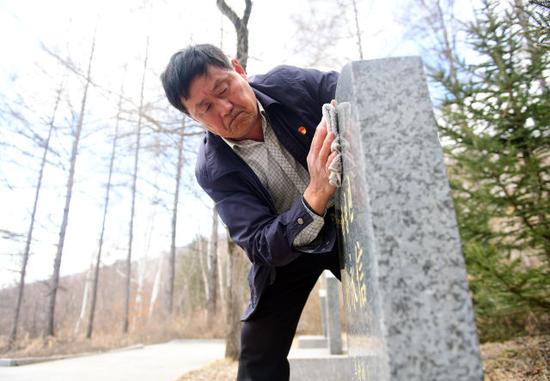 刘国信擦拭烈士墓碑。