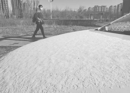 气温下降,4月13日清晨停靠在路边的汽车上覆盖了一层冰雪