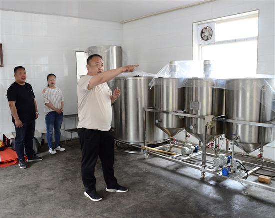 肖明君与驻村队员陈庆和李淑花在榨油厂现场讲解