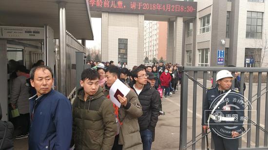 排在校内队伍里的家长们,手握号码牌、户口本等排队办理入学手续。