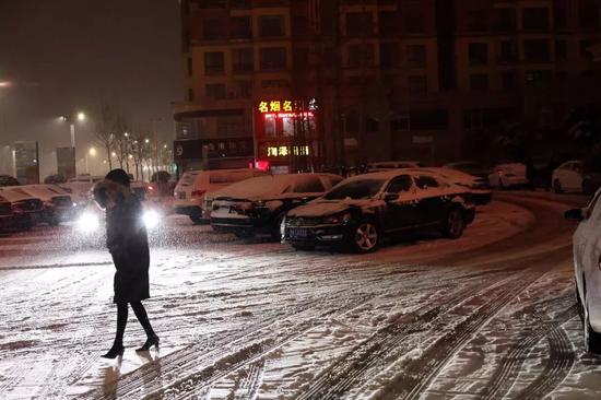 1月3日晚,河南许昌襄城县,风雪中裹着大衣出行的路人。
