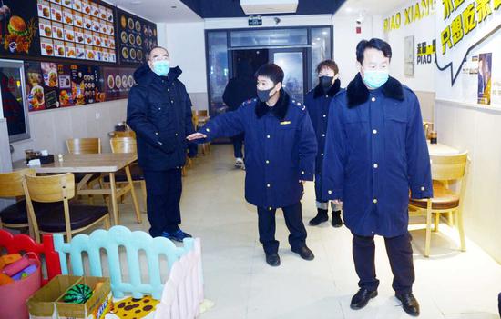 朱东俊(左二)对开业的餐饮店进行责令关闭