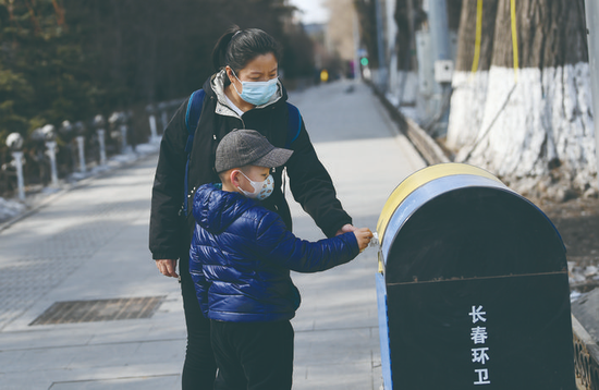 在自由大路上,一位小朋友将垃圾投入垃圾箱。 孙建一 摄