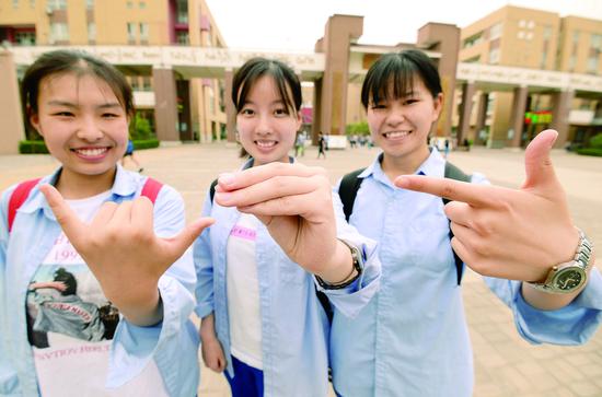 7日,在河北省邯郸市第一中学考点,三名考生摆出“678”手势,寓意“录取吧”。 (新华社发)