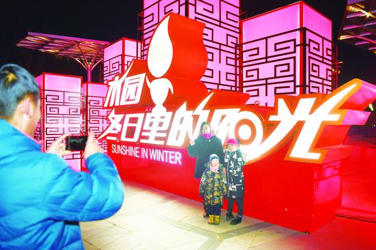灯光字前,一位市民为妻子及子女拍照留念。