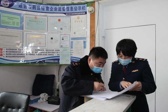 韩杨（右）与同事对药店进行检查登记