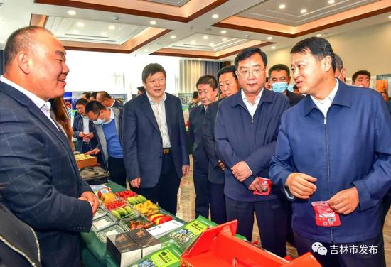 吉林市委书记王庭凯(右一)、市长贺志亮(左二)在吉白两市扶贫产业协作对接洽谈会上,观看了解扶贫对接企业的产品。
