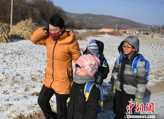 梁淑华送学生回家，她将自己的帽子拿给学生戴，自己用手御寒。　苍雁 摄