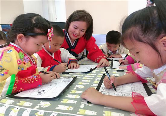 新蕾教师指导幼儿用手中的画笔,描绘美丽家乡