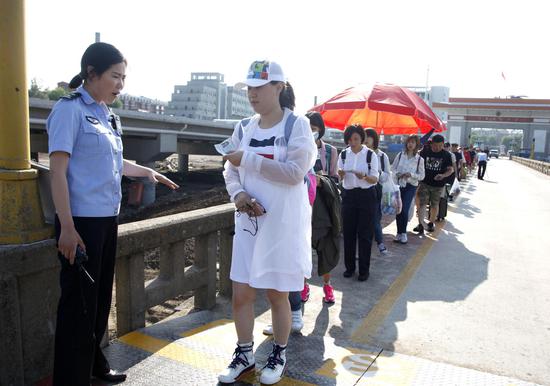 7月19日，吉林图们口岸公路桥通道，边检民警查看出境游客证件。