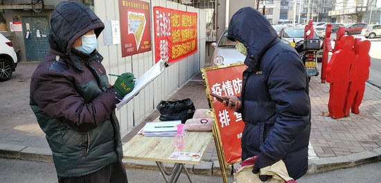 刘凯在值勤点对进入小区居民进行登记并发放通行证