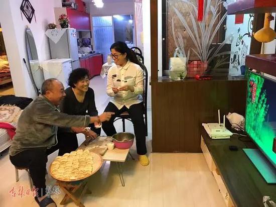 通化观众朱永富与家人一起一边包饺子,一边看央视春晚吉林长春一汽分会场的演出。