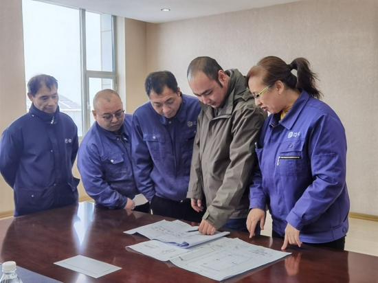 设计人员正在根据图纸商讨施工方案