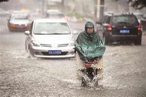市民在雨中骑行。张扬 摄