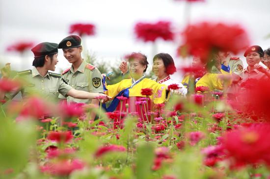 8月15日，在图们市日光山花海景区，边防官兵与朝鲜族老人漫步在花海美景中。