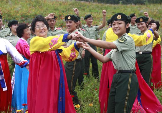 8月15日，在图们市日光山花海景区，边防官兵与朝鲜族老人在花海中载歌载舞。