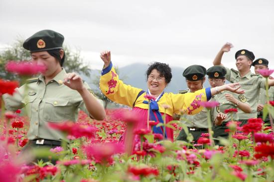 8月15日，在图们市日光山花海景区，边防官兵与朝鲜族老人漫步在花海美景中。