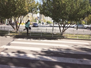 一名女子跨过挡路的铁栅栏。李子涵 摄