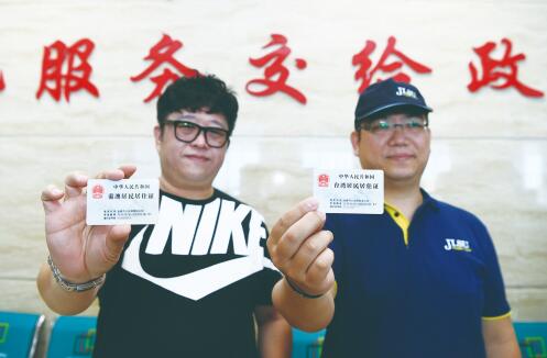 11日,在市公安局朝阳区分局户政大厅,来自香港的李志伟(左)和来自台湾的李豪杰,领取了我省首批港澳台居民居住证。 孙建一 摄