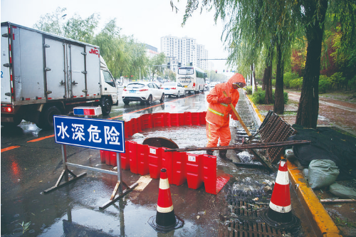 9月8日，光谷大街与众恒路交会处积水点，防汛人员利用防洪挡疏导积水。 张扬 摄