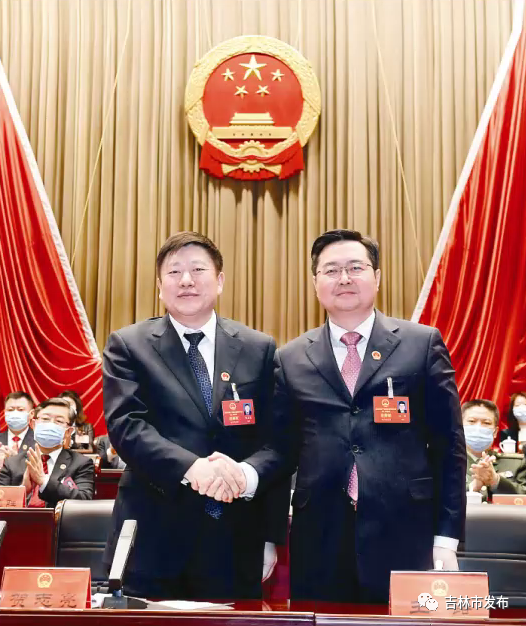 吉林市委书记贺志亮(左)与新当选的吉林市人民政府市长王路握手表示祝贺。