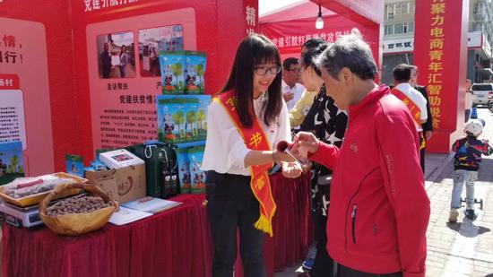 2018年9月,刘宇恒(左)在四平市第一书记代言展销会介绍榛子。