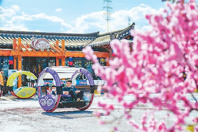 吉林省延边朝鲜族自治州和龙市“金达莱”民俗村,村民在村内的咖啡馆前体验亲子游乐项目。新华社记者 许畅摄