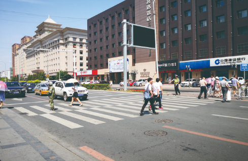 吉林大路亚泰超市门前，机动车停在斑马线外，等候行人通过。 张鑫多 摄