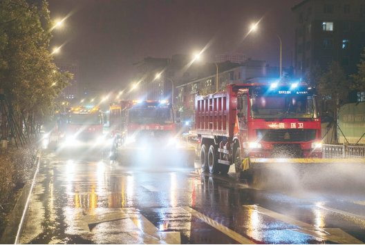 11月18日晚长春市民康路上环卫大型机械编队对路面进行扫水作业。