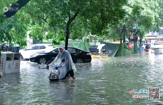 南昌市东湖区文教路一位市民推着电动车艰难的在水中的道路上前行