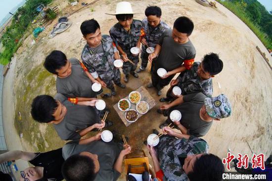 大溪乡民兵应急排巡堤人员围在一起吃晚饭。 王昊阳摄