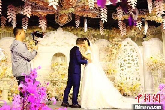 图为婚庆公司摄像人员正在拍摄婚礼仪式上的一对新人。 刘占昆 摄