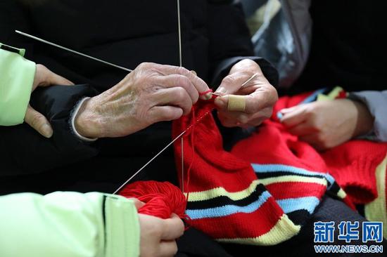 图为谢芝兰正在编织毛衣,手中棒针上下翻飞,动作娴熟。新华网 王凯丰 摄