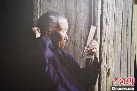 池煜华对着老镜子在百年老屋前梳妆。 兴国县委宣传部供图