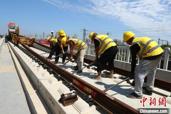 图为9月10日，施工人员在大型铺轨机的协助下，把长轨铺设在无砟道床上。　刘占昆　摄