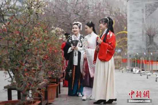 资料图:3月26日,身着汉服的女孩在北京陶然亭公园欣赏海棠花。中新社记者 杜洋 摄