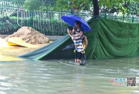 南昌一位市民背着家人涉水前行。