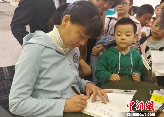 图为刘海云为孩童签名。 马爱彬 摄