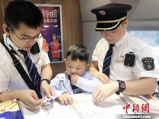 图为G2215次列车乘务人员陪伴小旅客做手工。 李丁 摄