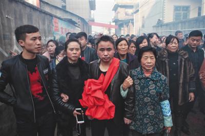 12月22日,乐平市中店村,方春平(戴大红花者)在亲友带领下回家,乡亲