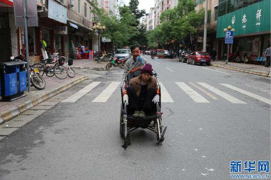 李根金用轮椅推着妻子散步。