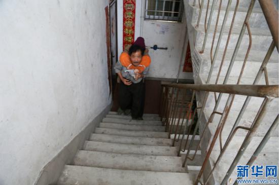 李根金背着妻子上楼,这对于住在六楼的李根金来说并非易事。