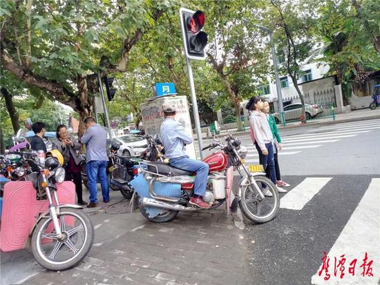 环城路与建设路交错口西边的人行道，南侧路口被摩托车、电动车堵塞