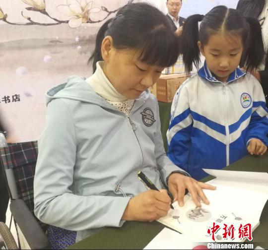 图为刘海云为孩童签名。 马爱彬 摄