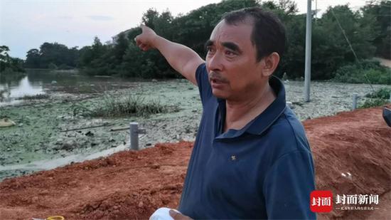 江西省鄱阳县双港镇双丰村村支书彭芳腊,向封面新闻记者讲述双峰南圩堤失守时,他带着官兵朝高处狂奔5公里的经过。 其身后是洪水漫过圩堤后,淹没了农田。