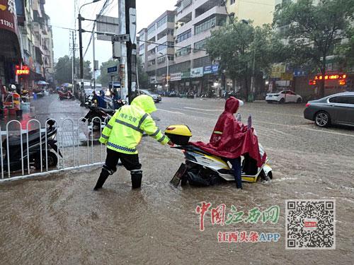 南丰县城,一电动车水中熄火,交警帮车主推车。图/朱树群 全媒体记者 舒晓燕