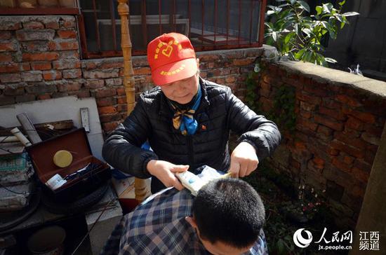 邹勤敏在居民的院子里为一名孩子理发